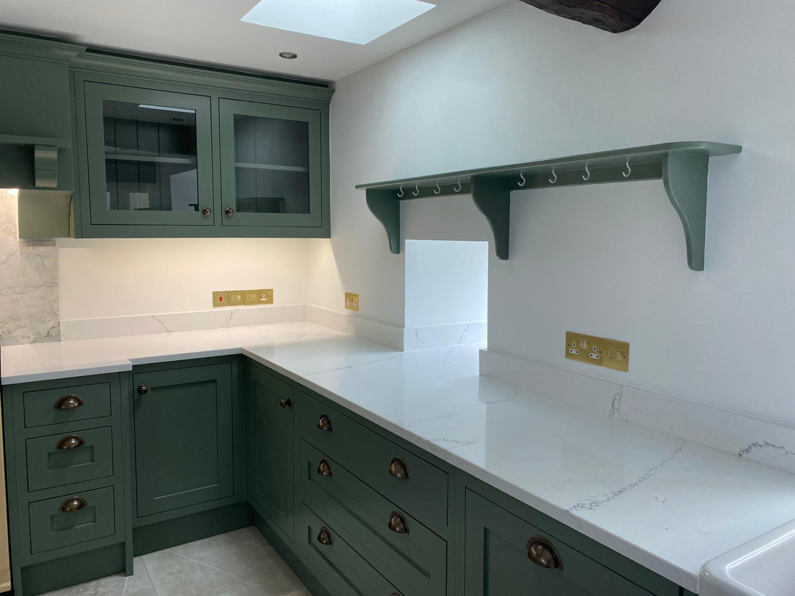 Green bespoke kitchen with white worktops