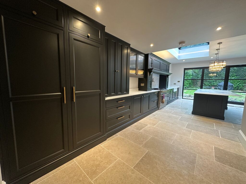Luxury bespoke kitchen design in Nottinghamshire featuring dark shaker-style cabinetry, marble worktops, central island, and modern skylight — by Tulip Kitchens.